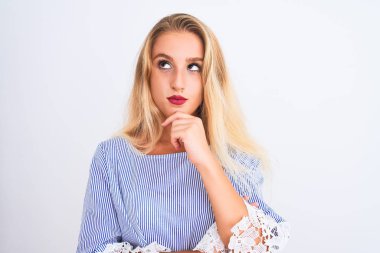 Young beautiful woman wearing elegant blue t-shirt standing over isolated white background serious face thinking about question, very confused idea
