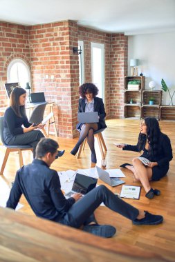 Bir grup iş adamı mutlu ve kendinden emin gülümsüyor. Yüzünde gülümsemeyle yerde rahatça oturmak. Birlikte çalışmak, belgeleri okumak ve ofiste konuşmak.