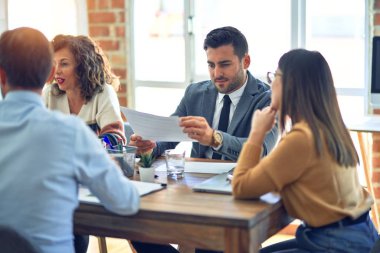 Group of business workers working together. Sitting on desk reading documents at the office