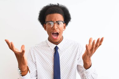 Kravat ve gözlük takan genç Afrikalı Amerikalı iş adamı beyaz arka planda çılgınca bağırıyor ve bağırıyor. Saldırgan ifadeler ve kollar havada. Hayal kırıklığı konsepti.