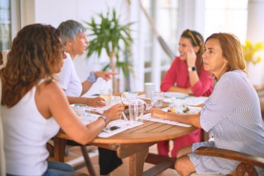 Genç ve güzel bir kız mutlu ve kendinden emin bir şekilde terasta oturmuş bir fincan kahve içiyor.