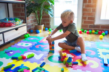 Anaokulunda oyuncaklarla oynayan beyaz bir çocuk. Anaokulu