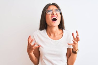 Genç, güzel bir kadın, izole edilmiş beyaz arka plan üzerine günlük tişört ve gözlük takıyor. Deli gibi bağırıyor, agresif bir ifade ve kollarla bağırıyor. Hayal kırıklığı konsepti.