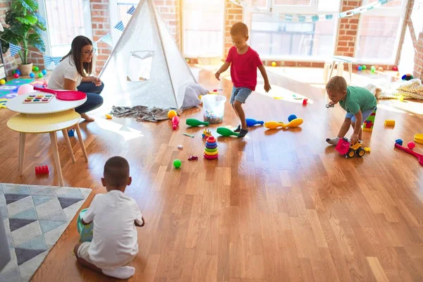 在幼儿园里 年轻漂亮的老师和蹒跚学步的孩子们在玩很多玩具 — 图库照片