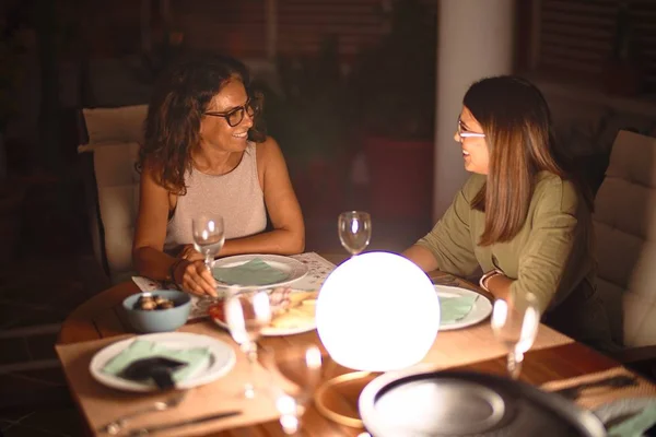 Beautiful mother and daughter on dinner smiling at terrace