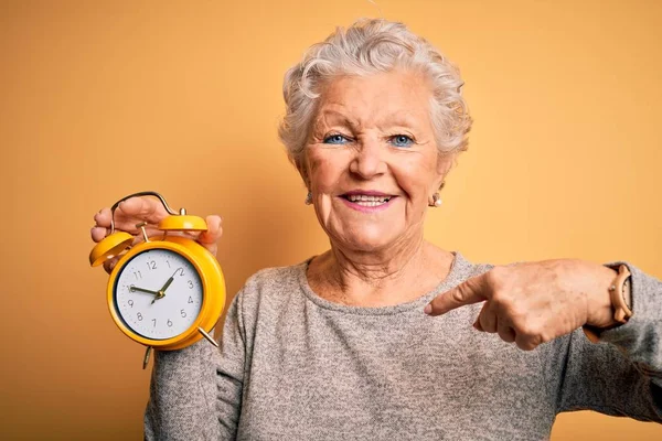 Senior Mooie Vrouw Houden Wekker Staande Geïsoleerde Gele Achtergrond Met — Stockfoto