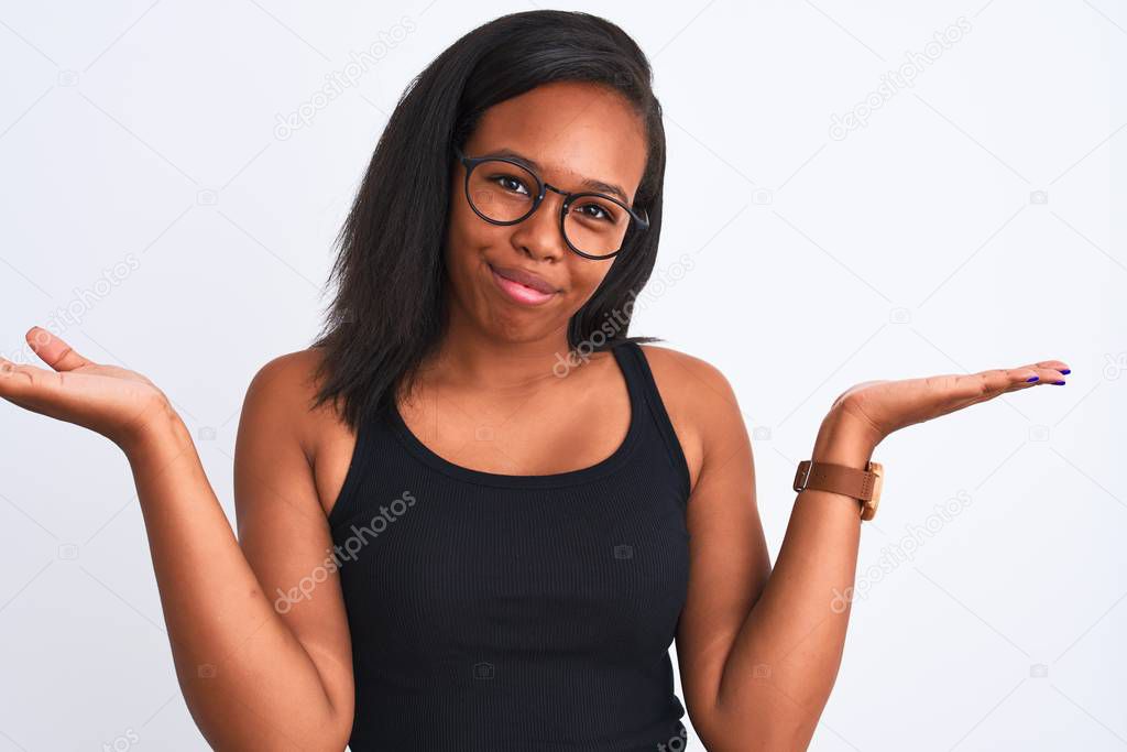 Beautiful young african american woman wearing glasses over isolated background clueless and confused expression with arms and hands raised. Doubt concept.