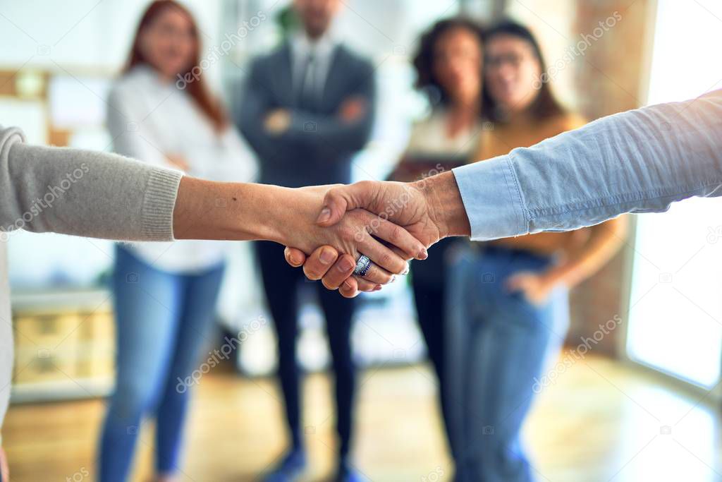 Group of business workers standing together shaking hands at the office