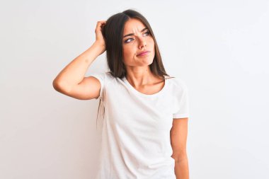 Young beautiful woman wearing casual t-shirt standing over isolated white background confuse and wondering about question. Uncertain with doubt, thinking with hand on head. Pensive concept.
