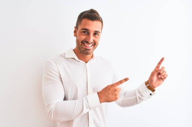 Soyutlanmış arka planda zarif gömlekler giyen genç yakışıklı iş adamı gülümseyip kameraya bakıyor ve iki eliyle ve parmaklarıyla kenarı işaret ediyor..