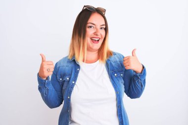 İzole edilmiş beyaz arka plan başarısı tabelasının üzerinde duran kot gömlek giyen güzel bir kadın. Elleriyle olumlu jest yapıyor. Gülümsüyor ve mutlu. Neşeli ifade ve kazanan jest.