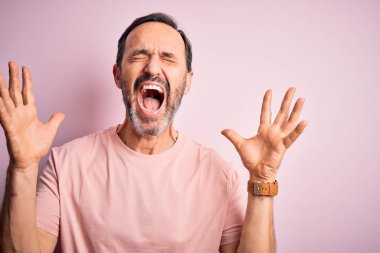 İzole edilmiş pembe arka planda dikilmiş, kollarını kaldırmış, gözlerini kapatmış heyecanlı çığlıklar atarak başarıyı kutlayan orta yaşlı, ağlak bir adam. Kazanan konsept