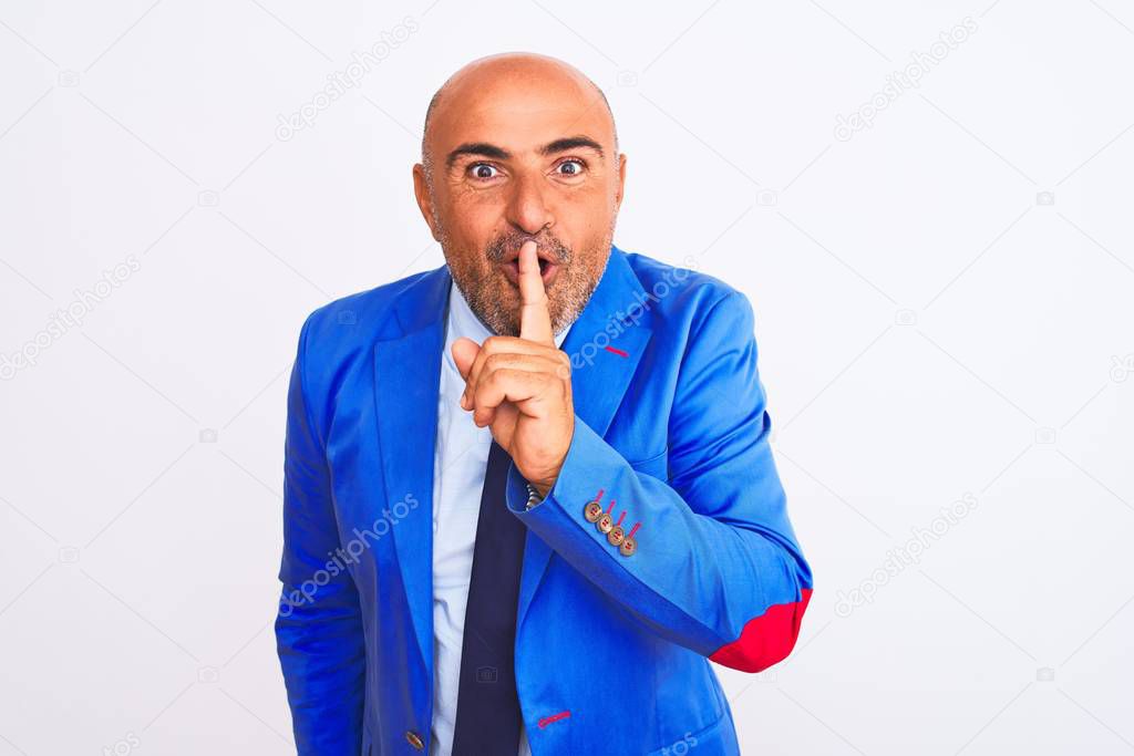 Middle age businessman wearing suit standing over isolated white background asking to be quiet with finger on lips. Silence and secret concept.