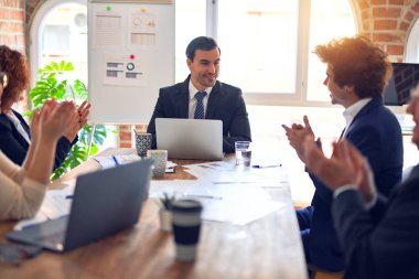 Bir grup iş adamı toplantıda mutlu ve kendinden emin gülümsüyor. Birlikte çalışarak sunuma bakacağız. Ofiste alkış tutacağız..