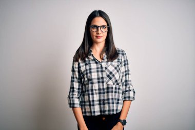 Mavi gözlü genç esmer kadın beyaz arka planda günlük gömlek ve gözlük takıyor. Uykulu ve yorgun görünüyor. Yorgun ve akşamdan kalma, tembel gözlü..