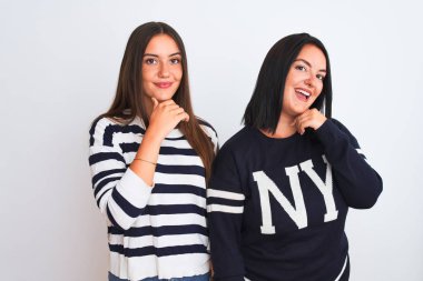 İzole edilmiş beyaz arka planda dikilen rahat kıyafetler giyen genç ve güzel kadınlar çapraz kollarla gülümseyen ve çenesini kaldıran kameraya güvenle bakıyorlar. Olumlu düşünüyorum..