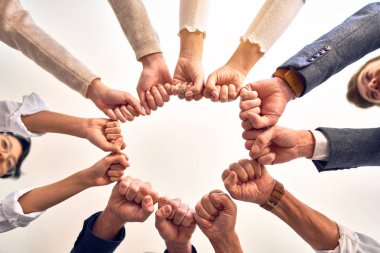 Bir grup işçi ofiste yumruk tokuşturuyor.