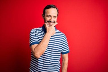 Orta yaşlı, beyaz, sıradan çizgili polo giyen, izole edilmiş kırmızı arka planda duran kolları çapraz ve çenesi havada kameraya gülümseyen bir adam. Olumlu düşünüyorum..