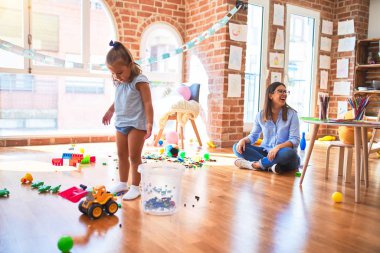 Beyaz kız çocuk, bayan öğretmenle oyun oynayıp öğreniyor. Anne ve kızı oyuncaklarla oyun odasında.