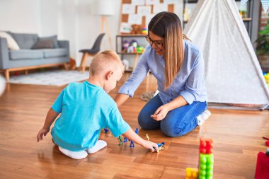 Genç beyaz çocuk öğretmeniyle oyun okulunda oynuyor. Oyuncak askerlerle oyuncak odasında oynamak.