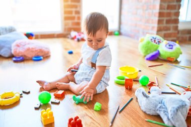 Anaokulunda bir sürü oyuncakla oynayan sevimli bir çocuk.
