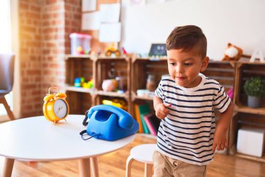 Güzel çocuk anaokulunda klasik mavi telefonla oynuyor.