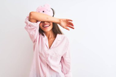 İzole edilmiş beyaz arka plan üzerinde uyku maskesi ve pijama giyen genç ve güzel bir kadın. Gözleri, neşeli ve komik gülümseyen bir kolla örtüyor. Kör kavram.