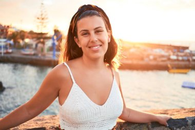 Güzel genç bir kadın kumsalda yürüyor okyanus manzarasının tadını çıkarıyor yaz tatilinde gülümsüyor.