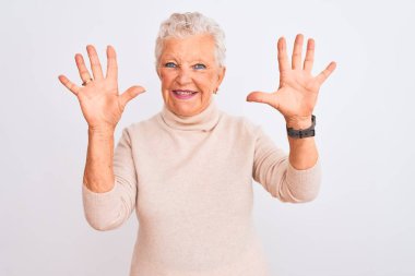 Senior grey-haired woman wearing turtleneck sweater standing over isolated white background showing and pointing up with fingers number ten while smiling confident and happy. clipart