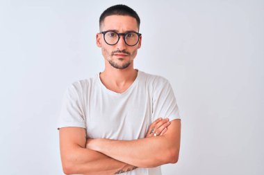 Young handsome man wearing glasses and standing over isolated background skeptic and nervous, disapproving expression on face with crossed arms. Negative person.