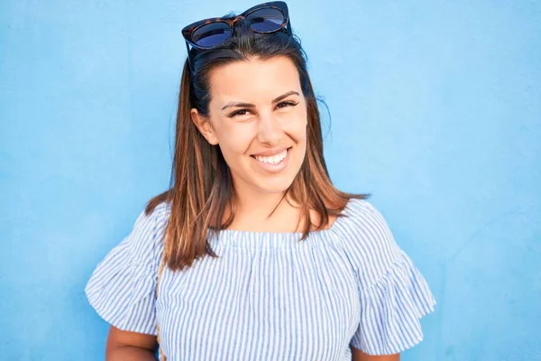 Beautiful girl leaning on blue wall, young friendly woman smiling happy on a sunny day of summer
