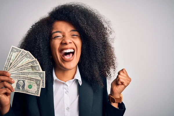 Afro saçlı Afrikalı Amerikalı genç bir iş kadını elinde para dolu banknotlarla gururla bağırıyor ve zaferi ve başarıyı kutluyor. Çok heyecanlı, coşkulu, coşkulu.