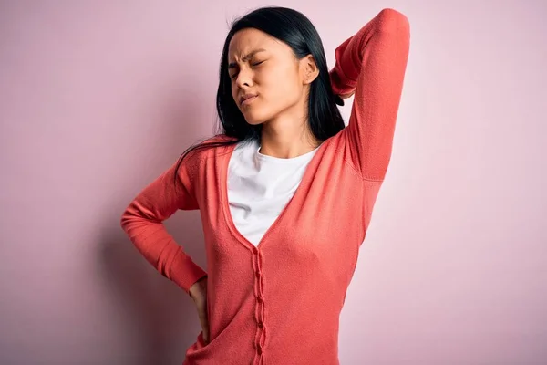 若いです美しい中国の女性身に着けていますカジュアルセーター上の隔離されたピンクの背景首の痛みの負傷 手で首に触れます 筋肉痛 — ストック写真