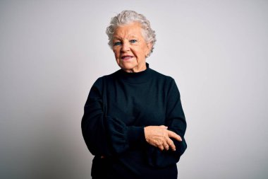 Son sınıf güzeli siyah kazak giyen, izole edilmiş beyaz arka planda duran, yüzünde gülümsemeyle, doğal bir ifadeyle yan yana bakan bir kadın. Kendinden emin gülen.