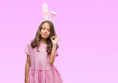 Esmer Latin kız Paskalya tavşan kulakları parmak, mükemmel sembolü ile ok işareti yaparken giyiyor