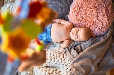 Evdeki battaniyenin üzerinde kanepeye uzanmış sevimli bir bebek. Yeni doğmuş bebek rahatlıyor ve dinleniyor.