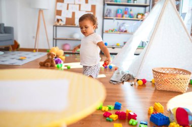 Anaokulunda bir sürü oyuncağın etrafına taş döşeyen sevimli bir çocuk.