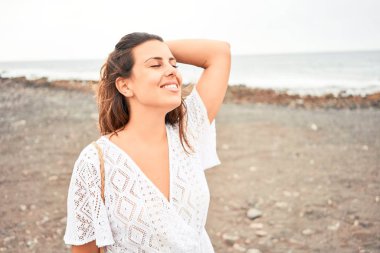 Genç ve güzel bir kadın gülümseyerek Kanarya Adaları 'ndaki siyah kumsalda yaz tatilinin tadını çıkarıyor.