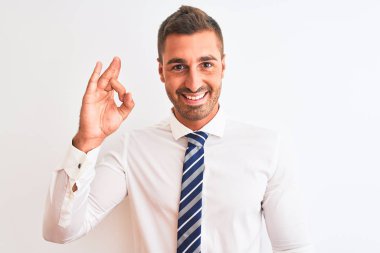 Genç yakışıklı, zarif bir iş adamı izole edilmiş arka planda gülümsüyor ve el ve parmaklarıyla 