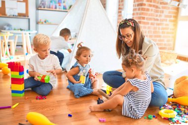 Güzel öğretmen ve bir grup çocuk anaokulunda bir sürü oyuncakla oynuyorlar.