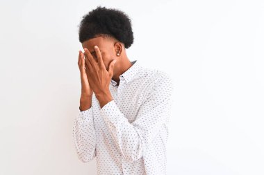 Zarif bir tişört giyen genç Afro-Amerikan erkek izole edilmiş beyaz arka planda duruyor. Üzücü bir yüz ifadesi var. Ağlarken yüzünü kapatıyor. Depresyon kavramı.