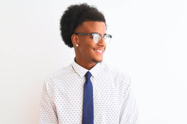 Genç Afro-Amerikan iş adamı kravat takıyor ve gözlük takıyor. İzole edilmiş beyaz arka planda. Yüzünde gülümseme, doğal bir ifade ile yan yana bakıyor. Kendinden emin gülen.