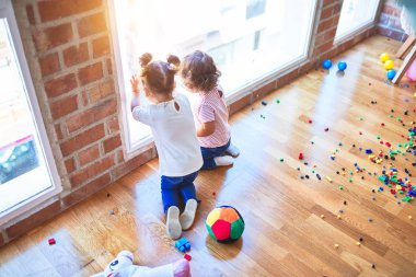 Anaokulunda bir sürü oyuncağın etrafından bakan sevimli bebekler.
