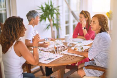 Genç ve güzel bir kız mutlu ve kendinden emin bir şekilde terasta oturmuş bir fincan kahve içiyor.