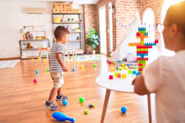 Güzel öğretmen ve küçük çocuk anaokulunda inşaat bloklarıyla oynuyorlar.