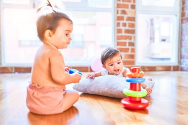 Güzel bebek mutlu kızlar, evde anaokulunda birlikte oynuyorlar, tahta zeminde oturuyorlar.