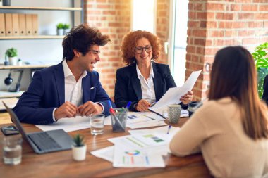 Bir grup iş adamı mutlu ve kendinden emin gülümsüyor. Ofiste dizüstü bilgisayarla çalışırken gülümseyerek konuşmak..
