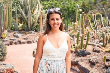 Güneşli bir yaz gününde yeşil kaktüs parkında mutlu ve neşeli gülümseyen güzel bir kadın.