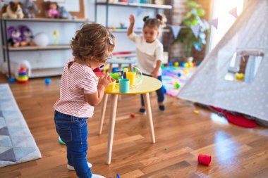 Anaokulunda plastik yemek ve çatal bıçak kullanarak yemek oynayan sevimli bebekler.