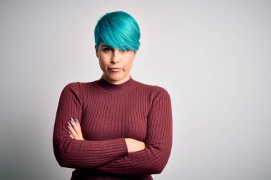 Young beautiful woman with blue fashion hair wearing casual sweater over white background skeptic and nervous, disapproving expression on face with crossed arms. Negative person.